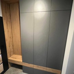 Aleksandra Szymborska CREO COMPANY - Nowoczesna zabudowa przedpokoju z szarą szafą wnękową i drewnianym siedziskiem z ażurową ścianką z pionowych listew.