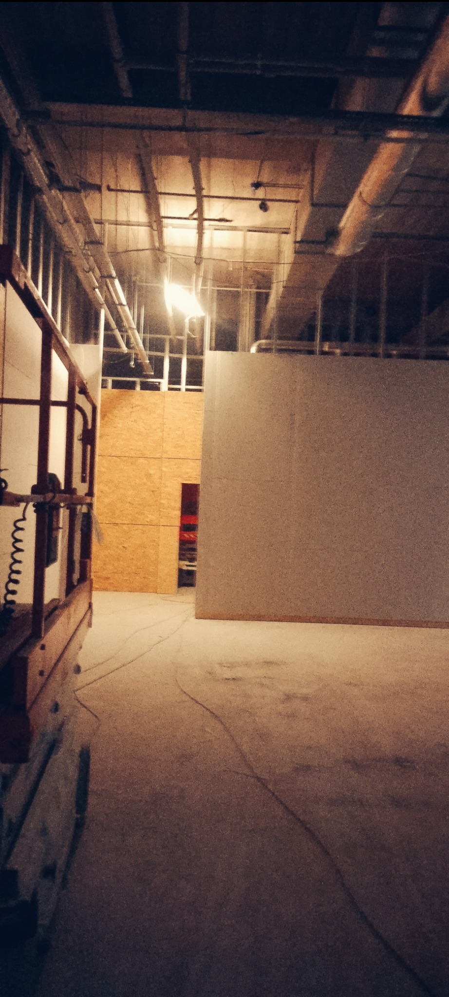 Wnętrze w trakcie prac wykończeniowych w Ciechanowie, widoczna konstrukcja ścian z płyt OSB, ściana przygotowana do malowania oraz podnośnik nożycowy.