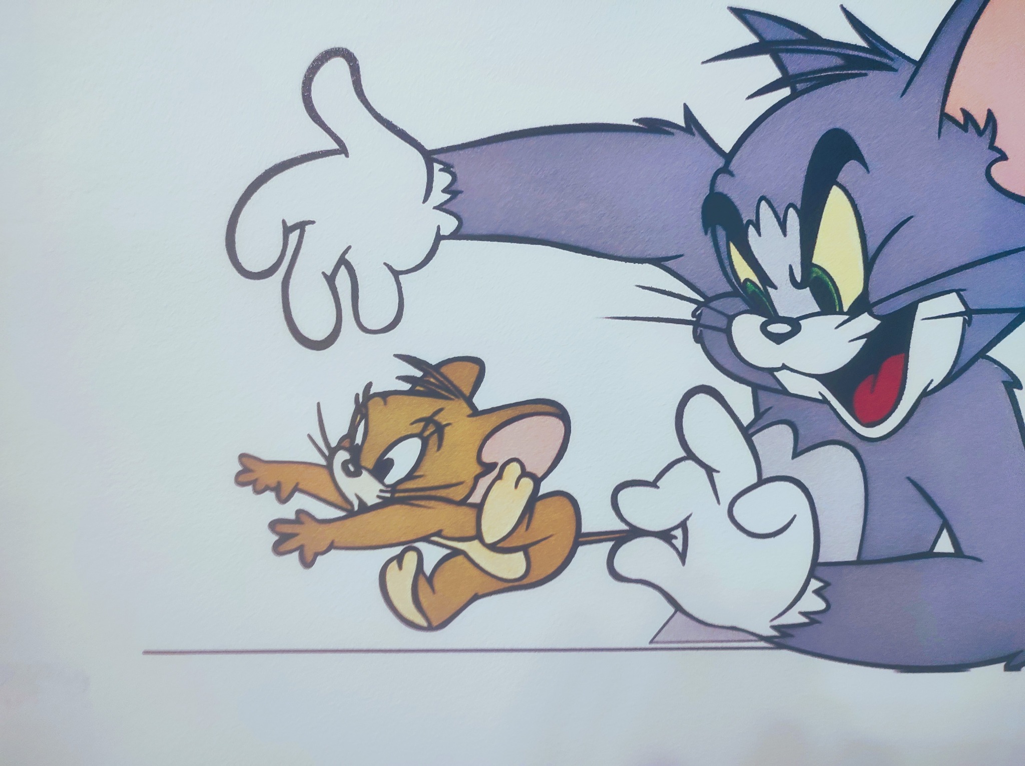 Ilustracja na ścianie przedstawiająca Toma i Jerry'ego; Tom próbuje złapać Jerry'ego.