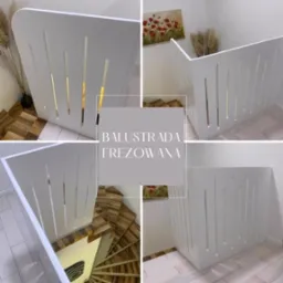 Biała, frezowana balustrada schodowa z pionowymi wycięciami, widok z góry na drewniane schody spiralne. Dekoracja wnętrza z obrazem i trawą pampasową w tle.