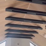 Nowoczesne schody metalowe z czarnymi stopniami i minimalistyczną balustradą, widok od dołu, podkreślający geometrię i design. Jasne tło.