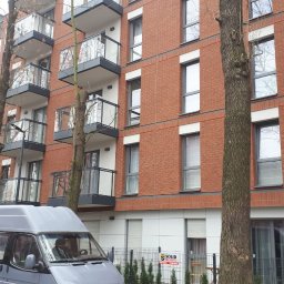 Chernyshov - Nowoczesny budynek mieszkalny z cegły z balkonami i szarym vanem serwisowym na pierwszym planie.