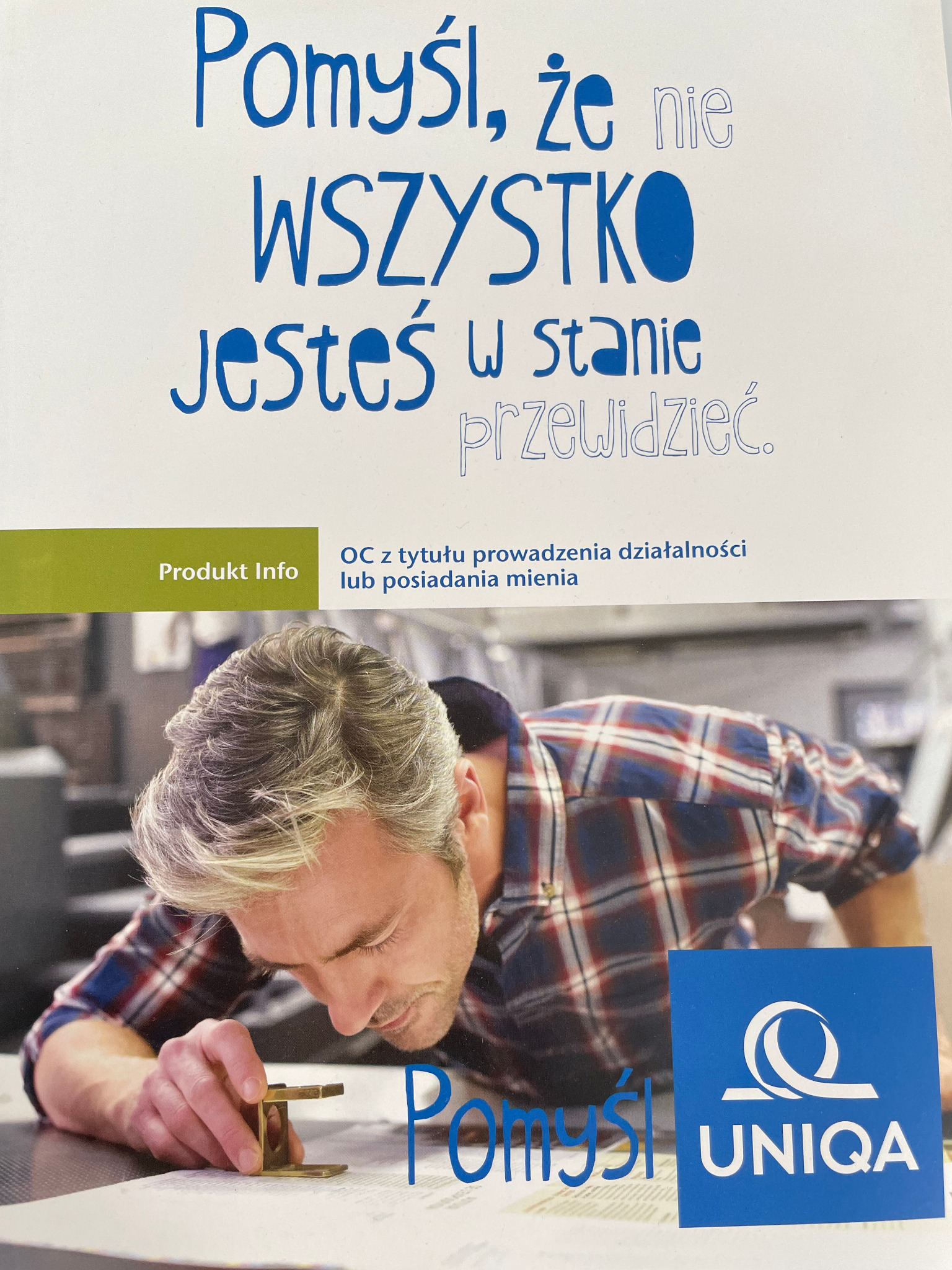 Zdjęcie przedstawia reklamę produktu, na której mężczyzna w koszuli w kratę przygląda się dokumentowi przez szkło powiększające, obok widnieje logo firmy ubezpieczeniowej UNIQA, a nad nim hasło...