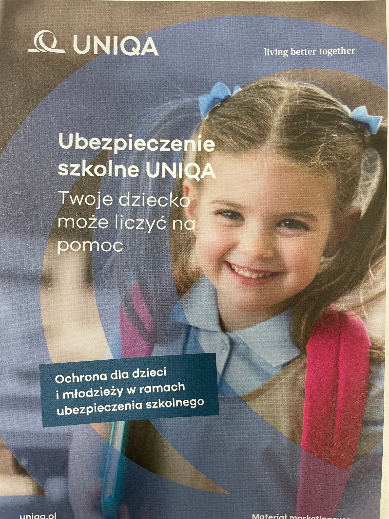 Uśmiechnięta dziewczynka w mundurku z plecakiem, promująca ubezpieczenie szkolne UNIQA na ulotce reklamowej.