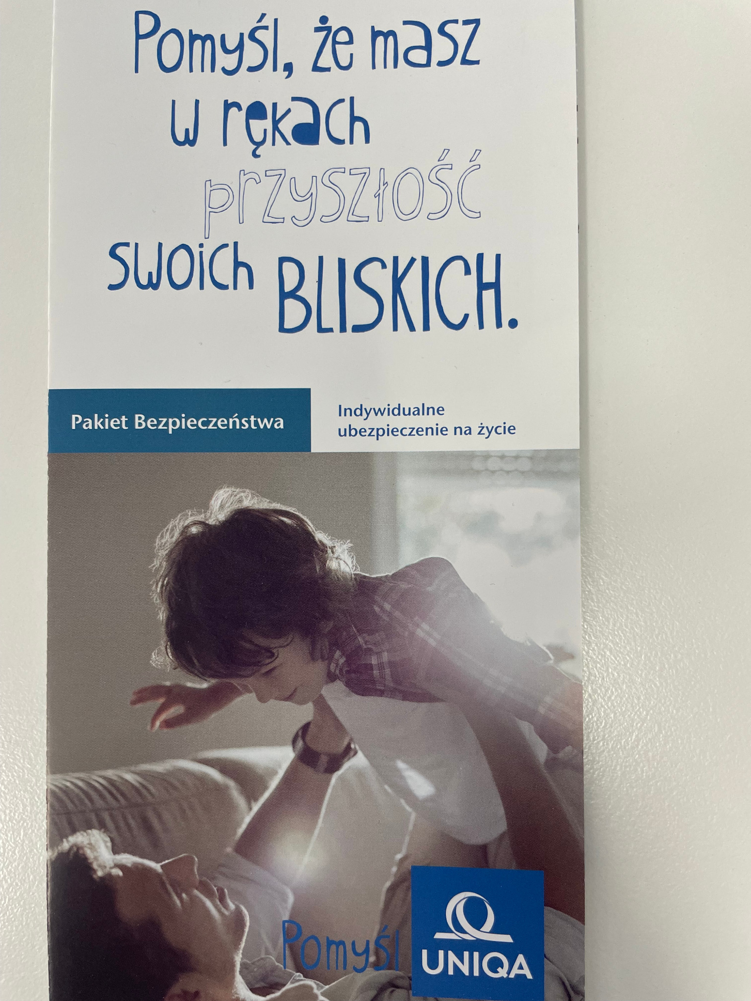 Ulotka reklamowa z hasłem 'Pomyśl, że masz w rękach przyszłość swoich bliskich', zdjęciem ojca i syna oraz logotypem Uniqa