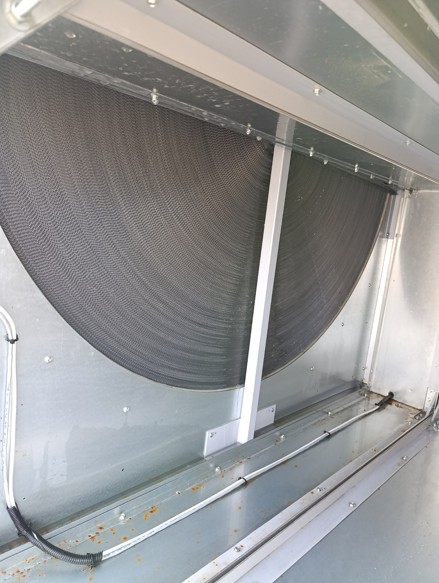Wnętrze kanału wentylacyjnego z filtrem, widoczne ślady korozji na metalowych elementach.