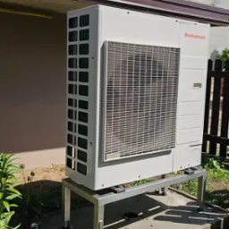 Zewnętrzna jednostka hybrydowej pompy ciepła Immergas Magis Combo Plus 9 V2 umieszczona na metalowym stelażu z regulowanymi nóżkami, na betonowej wylewce, z widocznym logo producenta.