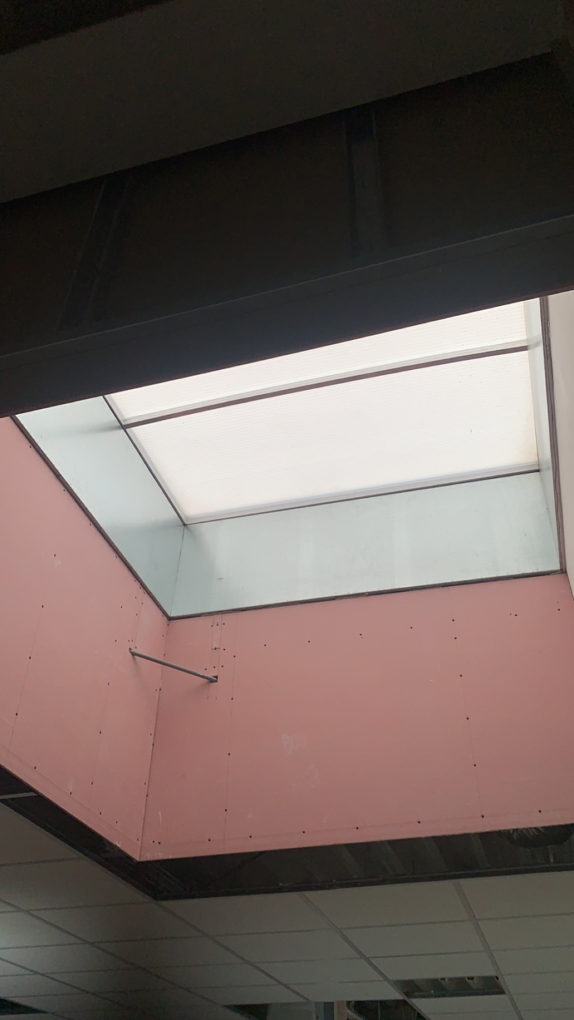 Montaż okna dachowego w pomieszczeniu z płytami kartonowo-gipsowymi, widoczny fragment sufitu kasetonowego.