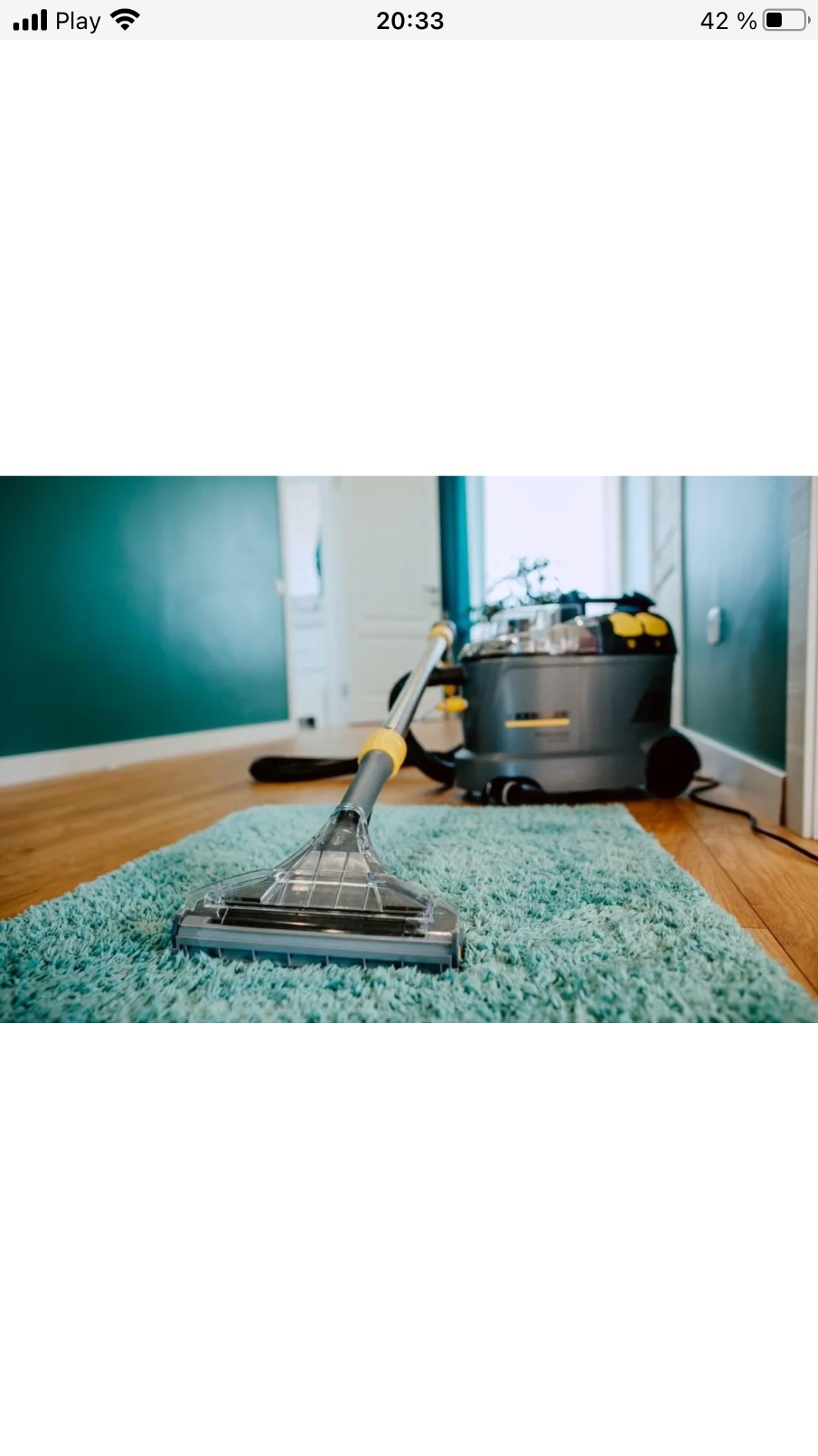 Dysza odkurzacza piorącego na turkusowym dywanie shaggy, widoczny fragment podłogi i ściany w tle.