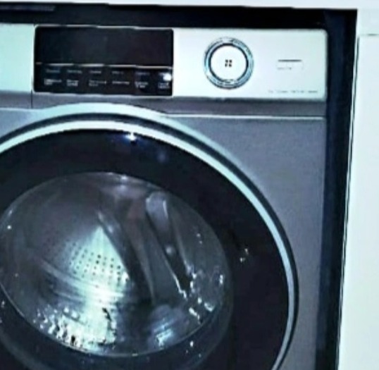 Nowoczesna pralka automatyczna z panelem sterowania i bębnem ze stali nierdzewnej, widoczna w łazience.