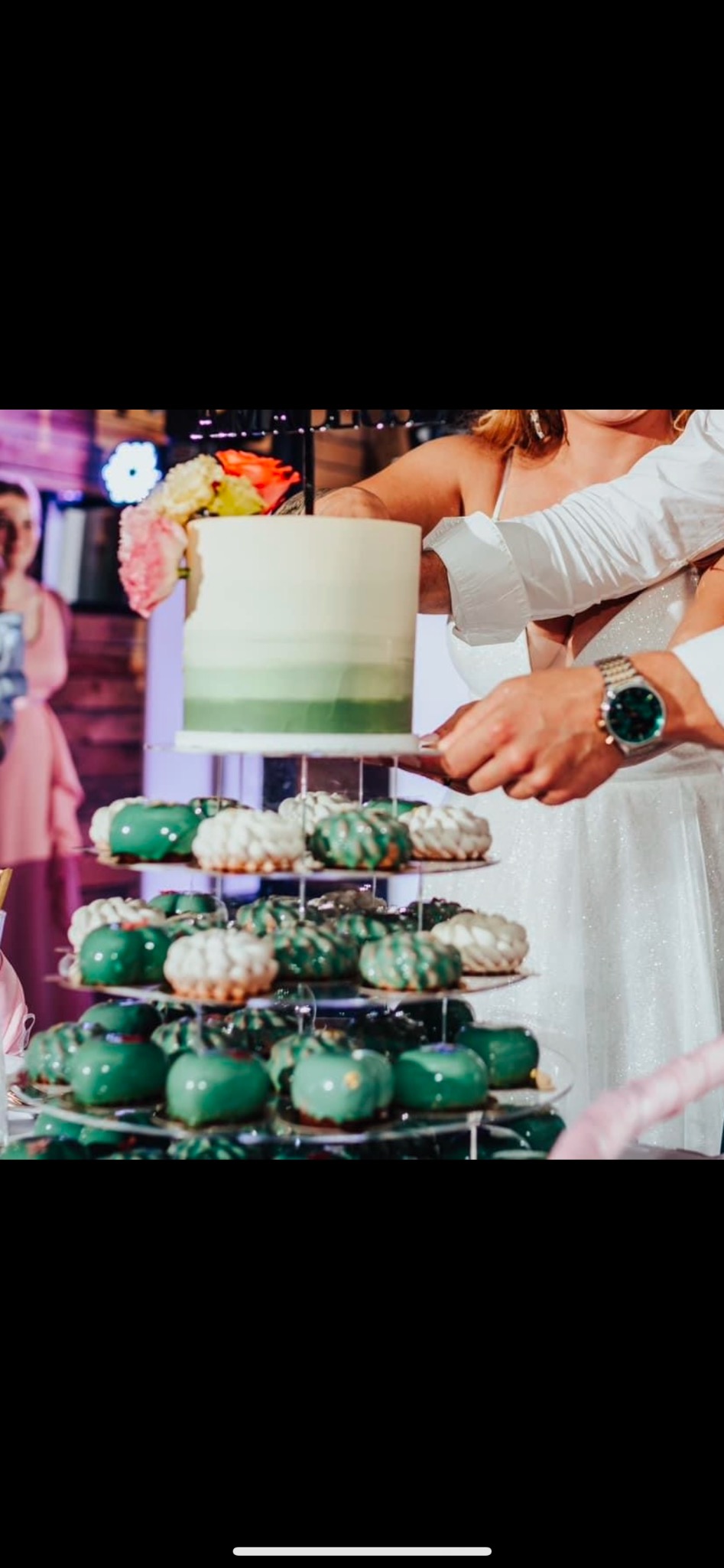 Nowożeńcy kroją tort weselny z zielonym ombre i piramidą zielonych i białych deserów na przezroczystym stojaku.