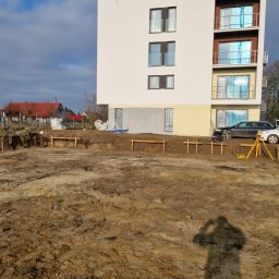 Usługi Geodezyjne Azymut - Tomasz Naworyta - Wytyczanie fundamentów pod budynek wielorodzinny w Wągrowcu. Widoczny niwelator na statywie i pracownik w trakcie pomiarów.