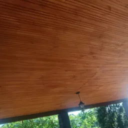 Drewniana podbitka dachowa z widocznymi lampami ogrodowymi, widok z zewnątrz, oświetlenie dzienne.