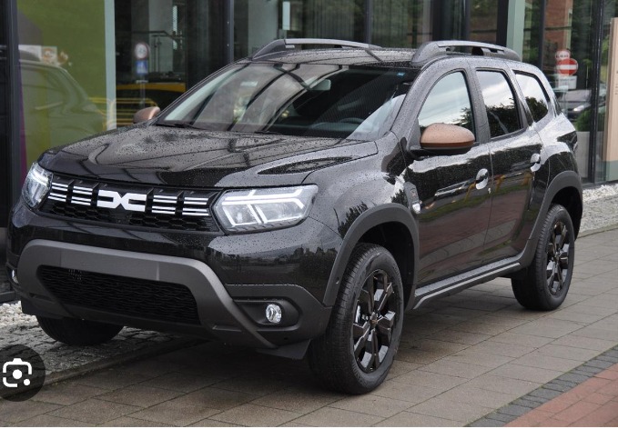 Czarny samochód Dacia Duster z brązowymi lusterkami na zewnątrz budynku z dużymi oknami.