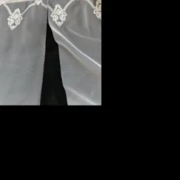 Delikatna, biała, siateczkowa firanka z koronkowym wykończeniem, z bliska, na czarnym tle.