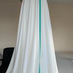 Zakład krawiecki Lussia Olha Mokrytska - Biała suknia ślubna w trakcie dopasowywania, przypięta szpilkami i zmierzona centymetrem krawieckim.