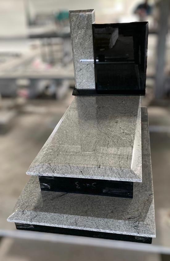 Nowoczesny, trzyczęściowy pomnik z szarego kamienia z czarnym, błyszczącym akcentem, widoczny w warsztacie kamieniarskim.