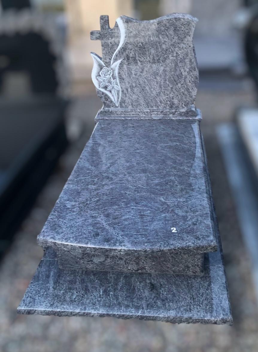 Granitowy nagrobek z wygrawerowanym krzyżem i motywem kwiatowym, widoczny numer '2' na płycie.