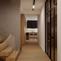 zacznij_od_wnetrza - Nowoczesny korytarz z drewnianymi schodami z podświetleniem LED, szklaną balustradą, czarną ścianką działową ze szkła i widokiem na kuchnię z barkiem i czarnymi szafkami.