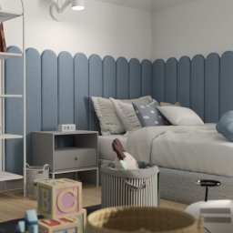 Natalia Wystup - Pokój dziecięcy z łóżkiem z niebieskim zagłówkiem w kształcie zaokrąglonych paneli, białym regałem z książkami i zabawkami oraz stolikiem nocnym z elektronicznym zegarem.