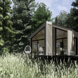 Architekt Karolina Radoń - Nowoczesny, minimalistyczny dom z drewna i dużymi przeszkleniami, otoczony lasem i wysoką trawą, z wiszącym fotelem na tarasie.