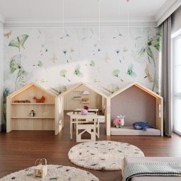 Architekt Karolina Radoń - Pokój dziecięcy z trzema drewnianymi konstrukcjami w kształcie domków, służącymi jako regały i miejsca do zabawy, stolik z krzesełkami, dywany z długim włosiem i tapeta w motywy roślinne i motyle.