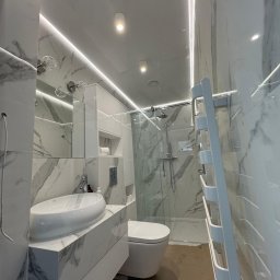 WoodyMAXX Sergiusz Proń - Wykończona łazienka z marmurowymi płytkami, podświetleniem LED, umywalką nablatową i kabiną prysznicową typu walk-in. Nowoczesny design z grzejnikiem drabinkowym.