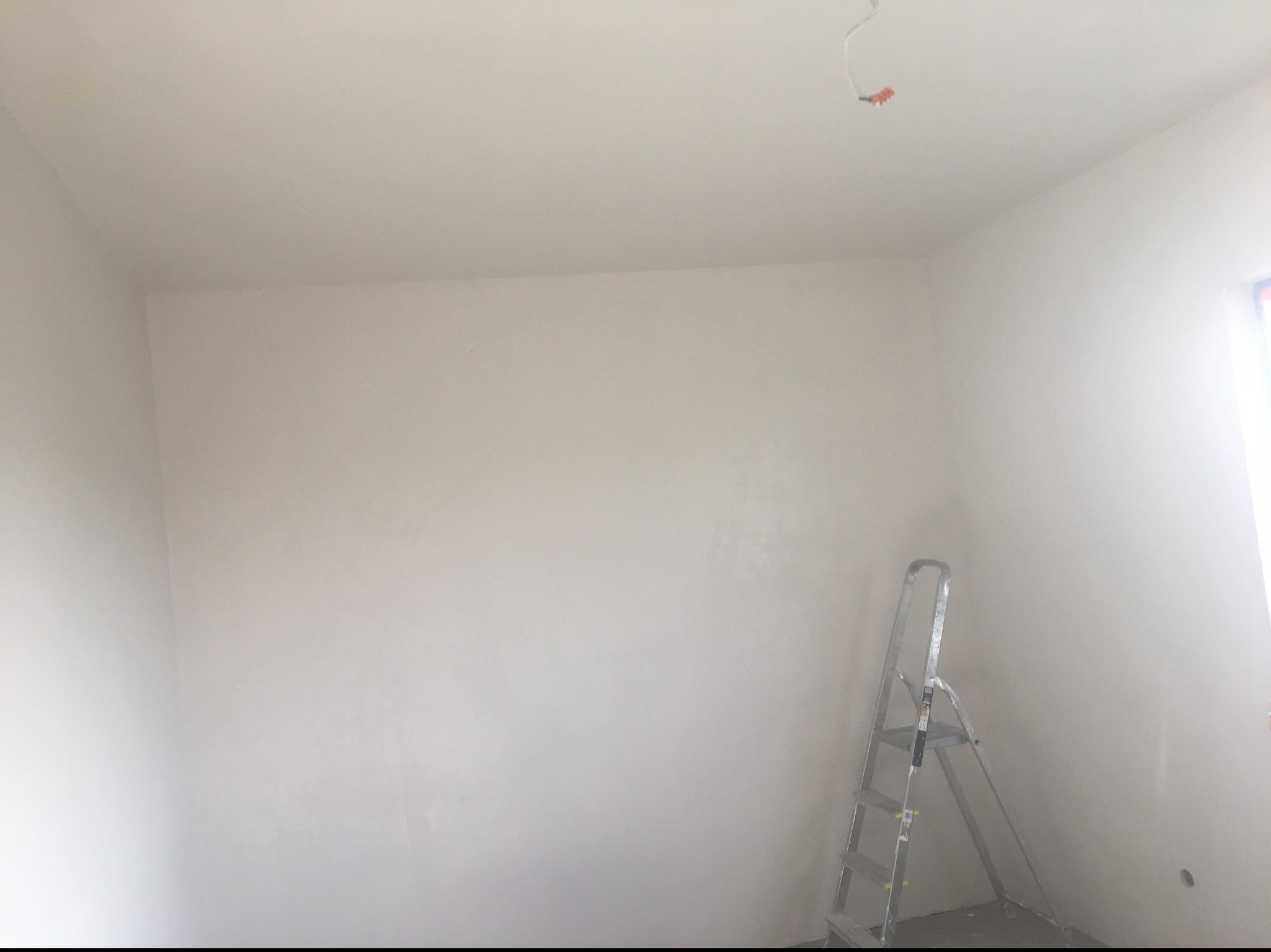 Pokój po szpachlowaniu w Poznaniu, ściany przygotowane do malowania, widoczna aluminiowa drabina.