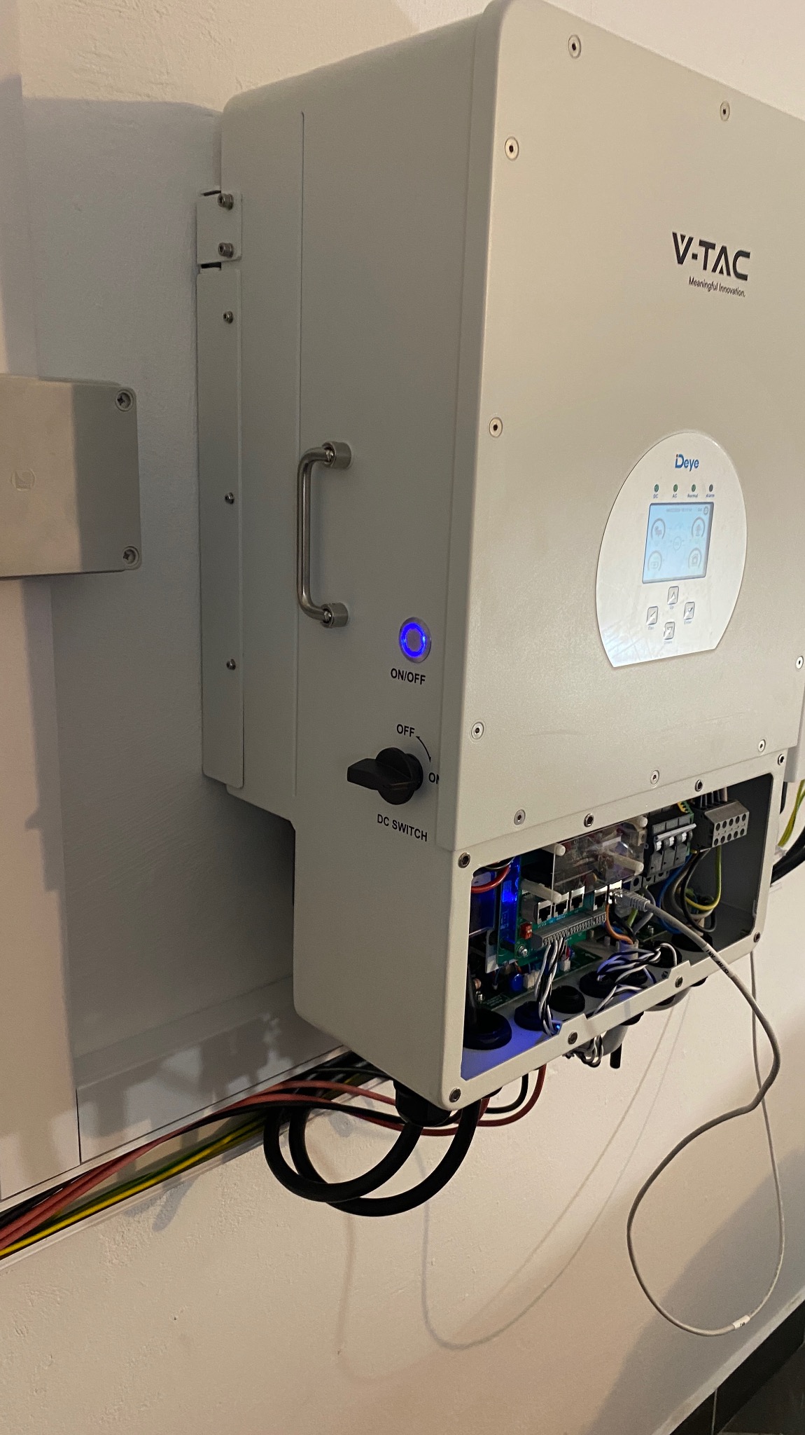 Zamontowany inwerter fotowoltaiczny V-TAC Deye z widocznymi przewodami i włączonym niebieskim podświetleniem przycisku ON/OFF.