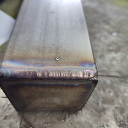 Ślusarskie usługi mobilne Łukasz Piekielniak - Detale spoiny na krawędzi metalowego profilu o przekroju prostokątnym, widoczne tęczowe przebarwienia termiczne.