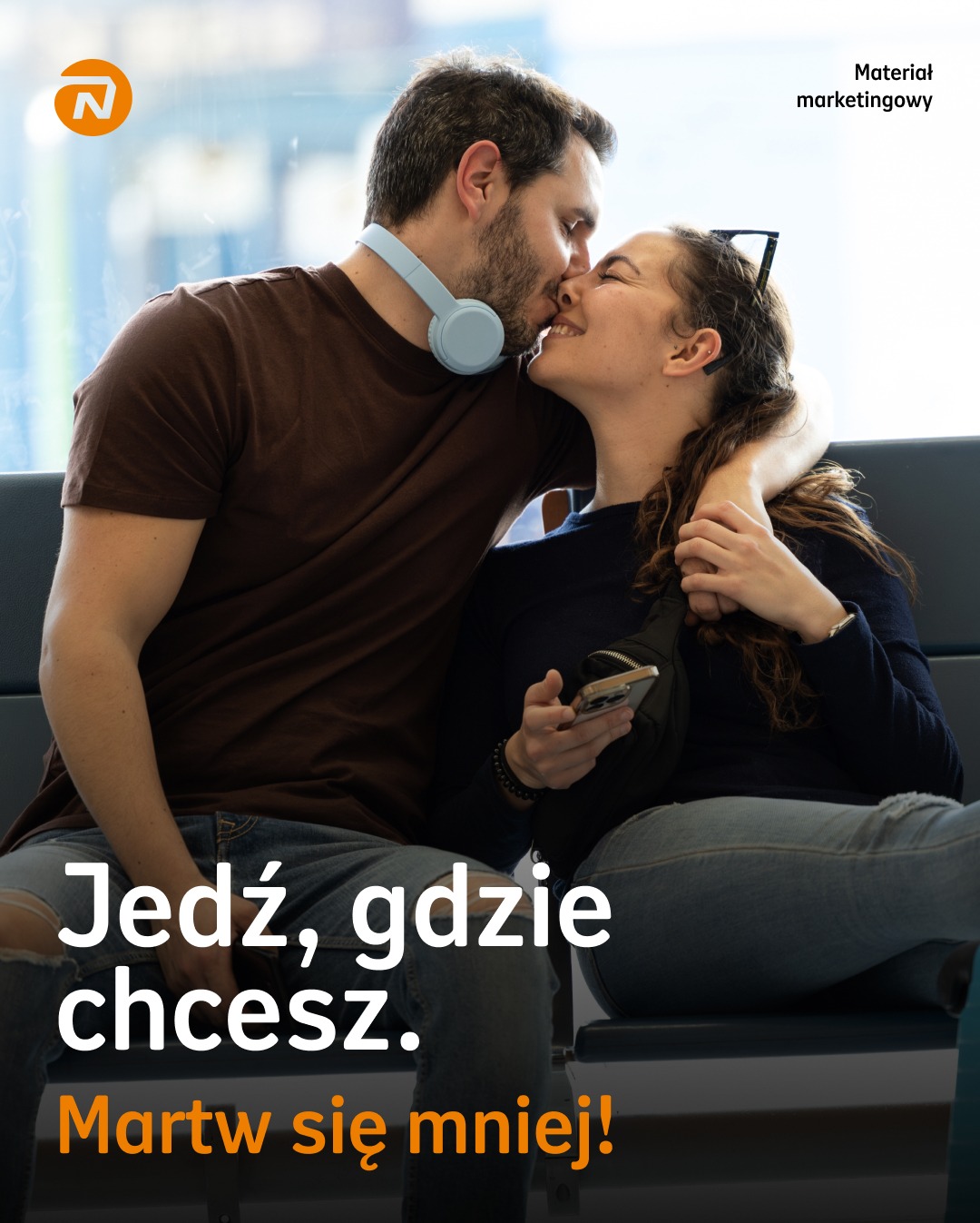 Para całująca się na lotnisku, hasło 'Jedź gdzie chcesz, martw się mniej!', sugerujące ubezpieczenie turystyczne.