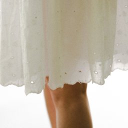 suzanephoto - Fragment sukienki z haftem angielskim i fragment nóg modelki na jasnym tle.