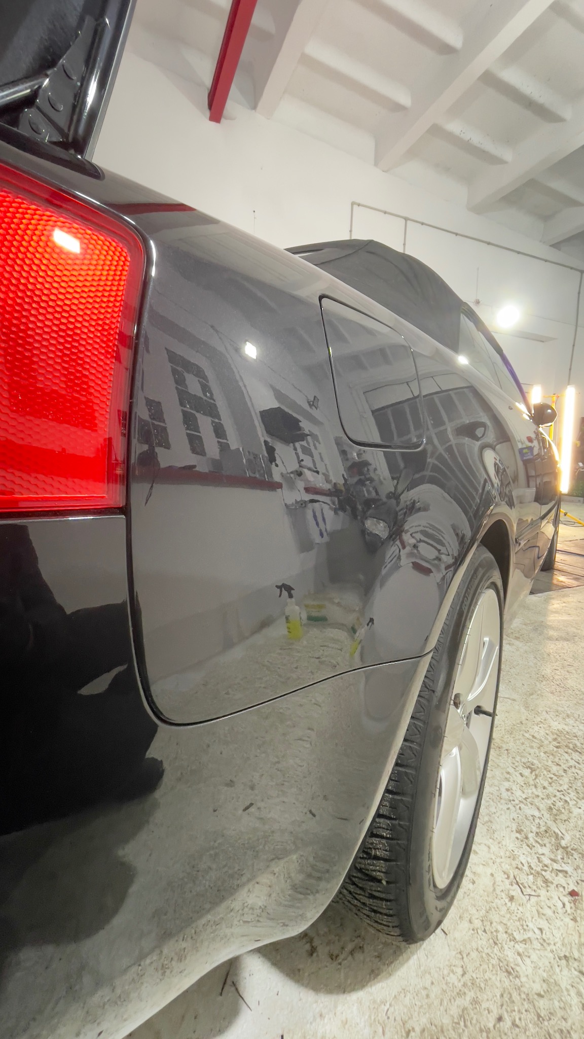 Szary samochód w warsztacie w Warszawie, widoczne ślady po polerowaniu lakieru i odbicie okien w karoserii.