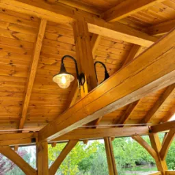 Drewniana altana z widoczną konstrukcją dachu i zamontowaną lampą w stylu retro z żarówką Edison