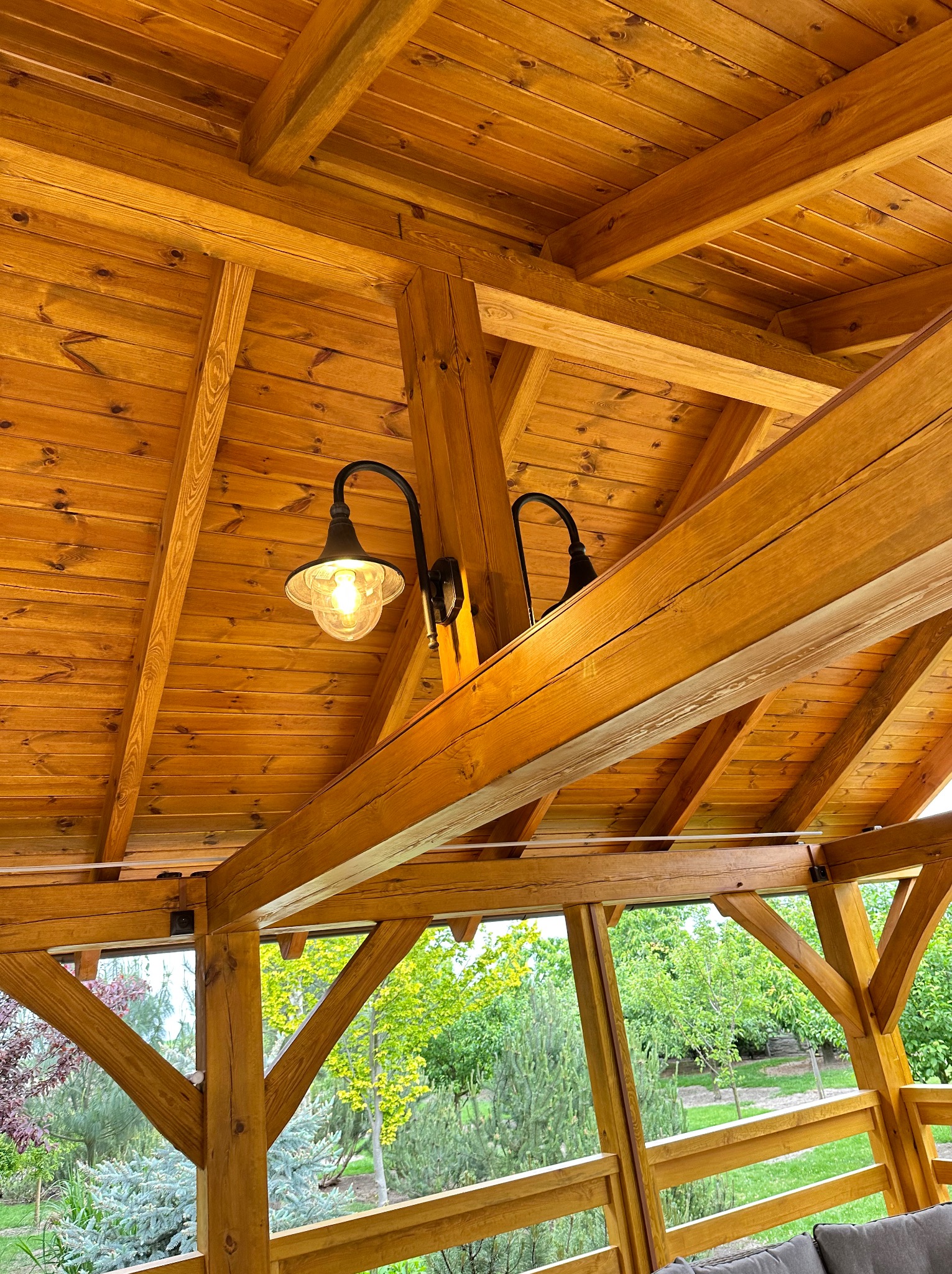 Drewniana altana z widoczną konstrukcją dachu i zamontowaną lampą w stylu retro z żarówką Edison