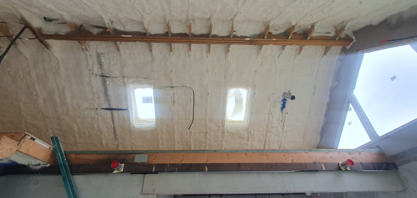 Poddasze po izolacji natryskowej w Krakowie. Widoczne okna dachowe i drewniana konstrukcja pokryta grubą warstwą piany. Izolacja wykonana z dbałością o detale.