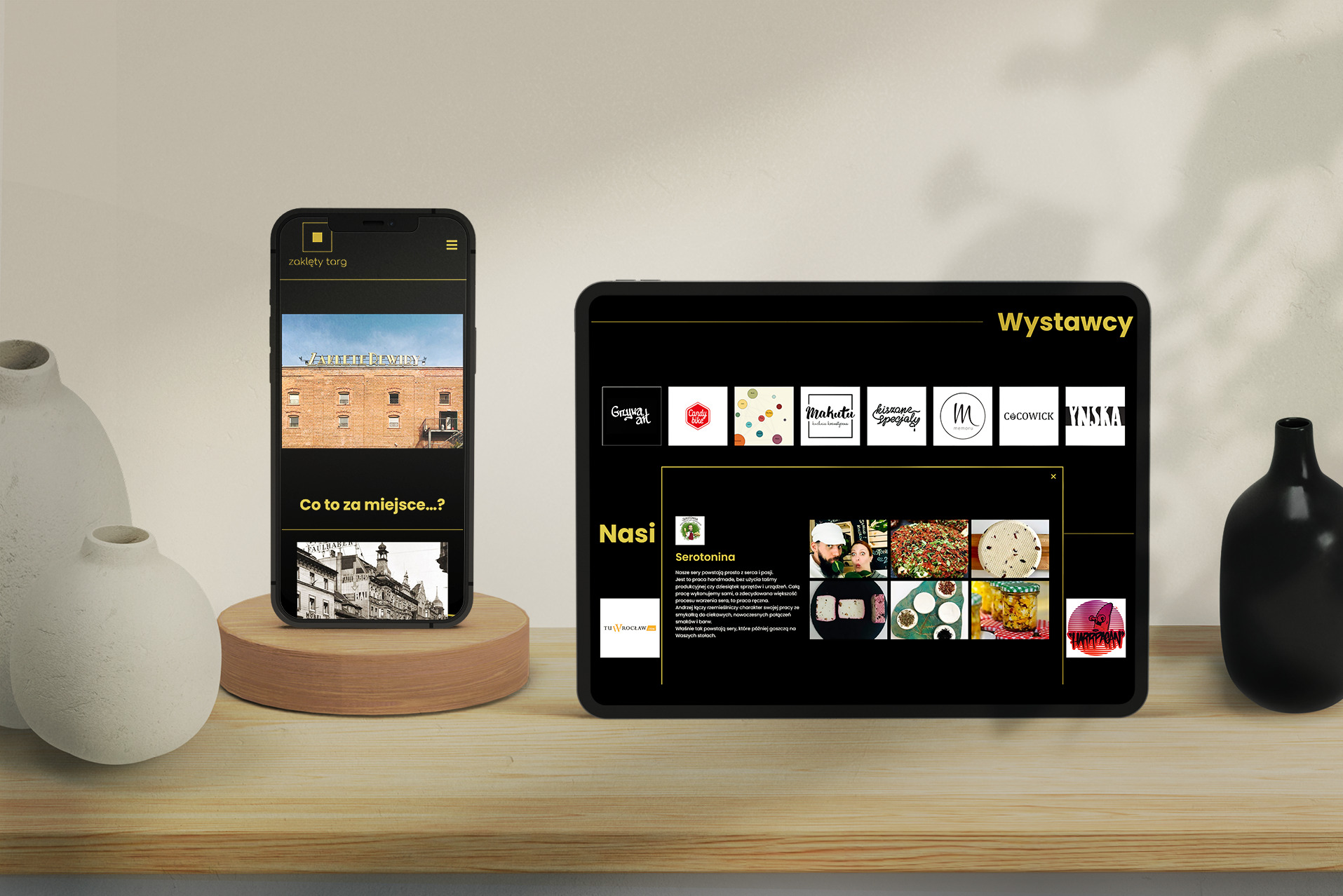 Prezentacja strony internetowej na tablecie i smartfonie z logo i ofertą lokalnych producentów żywności, wyświetlana na drewnianym stole z dekoracyjnymi wazonami.