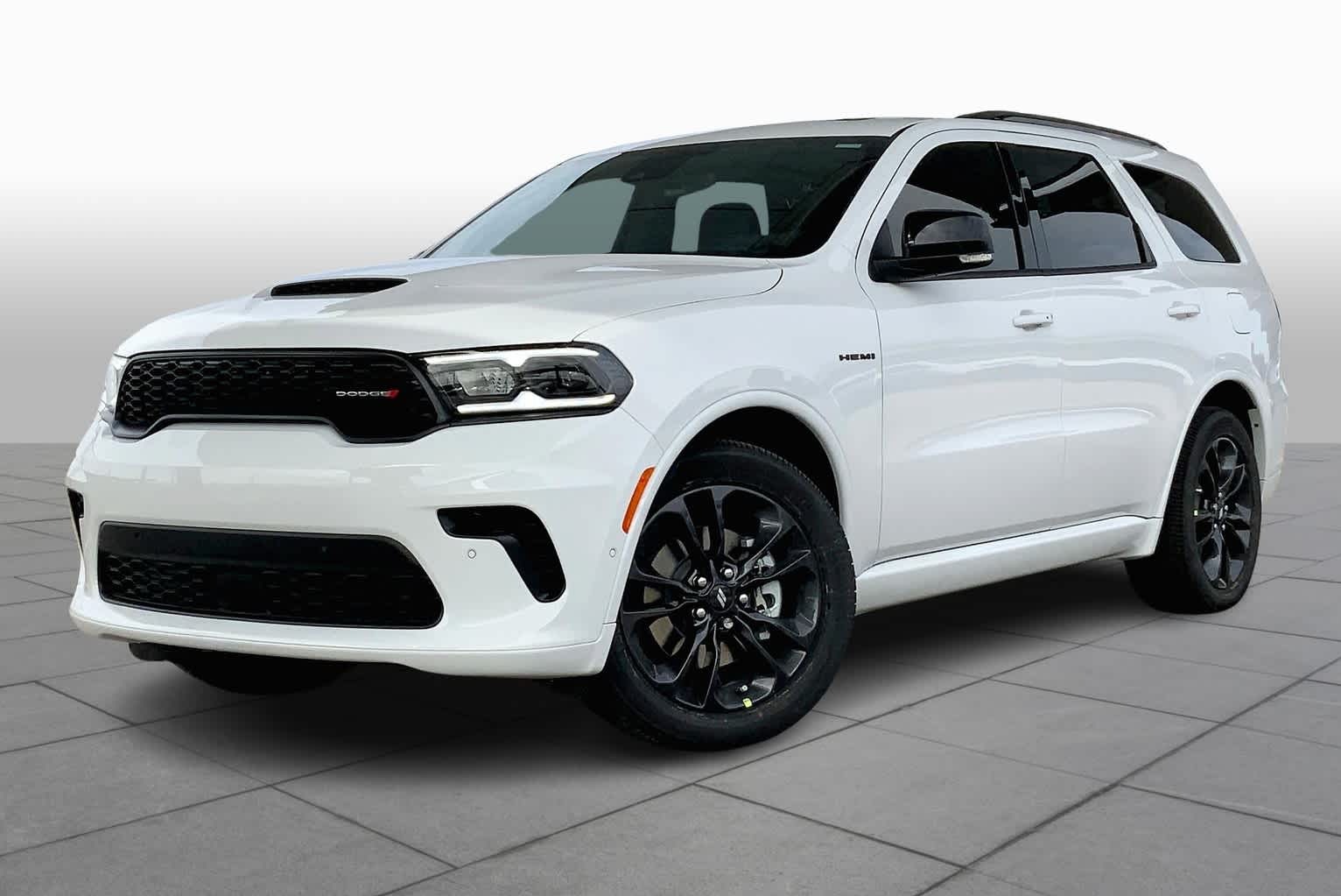 Biały samochód Dodge Durango z czarnymi felgami, widok z przodu i boku, na jasnym tle z płytek.