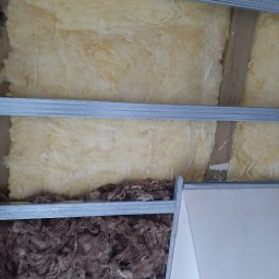 GREKBUD USŁUGI REMONTOWO-BUDOWLANE KACPER DOMŻALSKI - Ocieplenie poddasza wełną mineralną w metalowym stelażu, widoczna również płyta gipsowo-kartonowa.