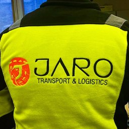 MTDesign Michał Tarnaski - Żółta bluza robocza z czarnymi ramionami, na plecach wyhaftowane logo firmy Jaro Transport & Logistics, z lewej strony logo w kształcie litery J z pomarańczowym wypełnieniem.