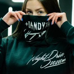 MTDesign Michał Tarnaski - Młoda kobieta w czarnej bluzie z kapturem z białym napisem 'Night Drive Szczecin' zasłaniająca twarz czarną chustą z białym napisem '+BANDYTHA #SZCZECIN', widoczne niebieskie paznokcie.