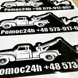 MTDesign Michał Tarnaski - Arkusze naklejek z czarno-białym logo przedstawiającym lawetę holującą samochód oraz napis 'Pomoc24h +48 573-917-057', widoczne pod kątem.