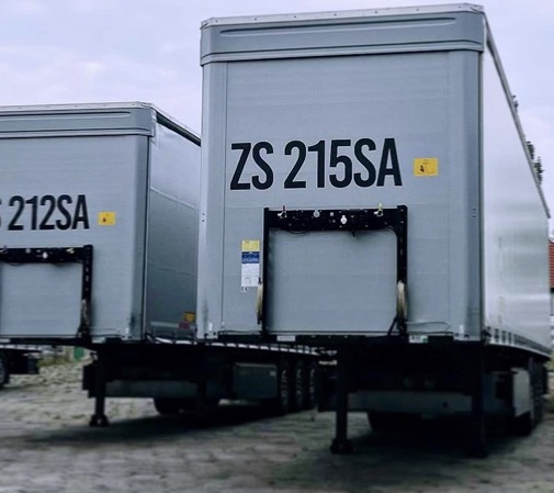 Dwie szare naczepy z czarnymi nadrukami numerów rejestracyjnych ZS 212SA i ZS 215SA, wykonane w Szczecinie.