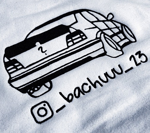 Biała koszulka z czarnym haftem przedstawiającym stylizowany samochód i nazwę użytkownika Instagrama '_bachuuw_23'.