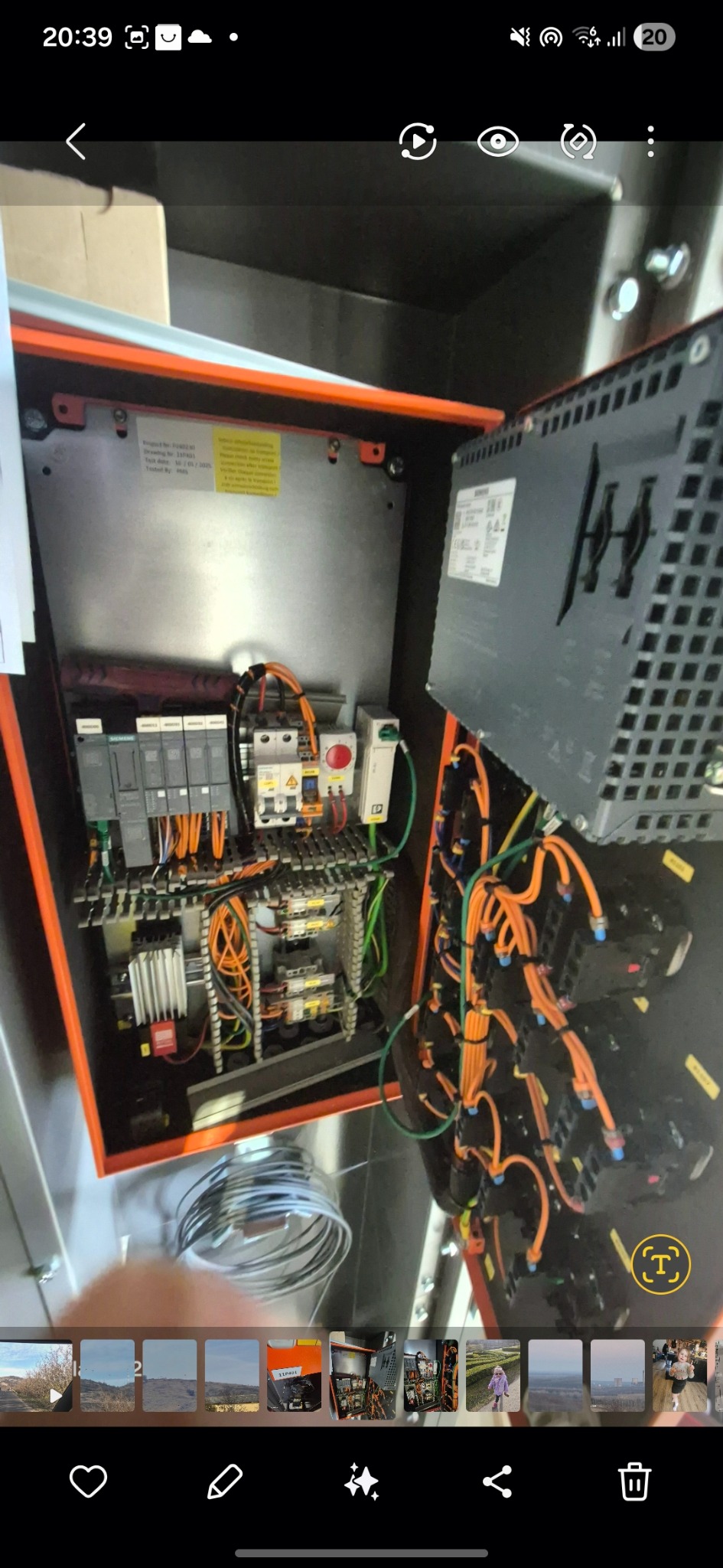 Otwarta, pomarańczowa szafa sterownicza z widocznymi elementami elektrycznymi, przewodami i modułami sterującymi. Widoczne kable w kolorze pomarańczowym i zielonym.