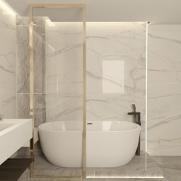 ARCHITEKTURA WNĘTRZ Jakub Tarnowski - Elegancka łazienka z wanną wolnostojącą, marmurowymi płytkami i złotymi akcentami, widok na umywalkę z dwoma kranami i okrągłym lustrem z ozdobnym oświetleniem.