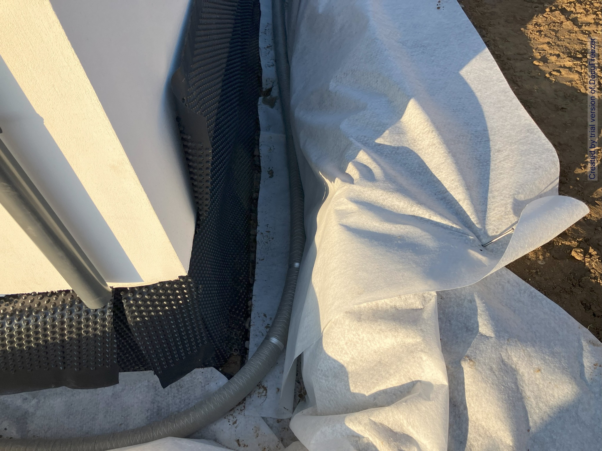 Izolacja fundamentów budynku w Lechowie: folia kubełkowa, geowłóknina i rura drenażowa podczas prac ziemnych.