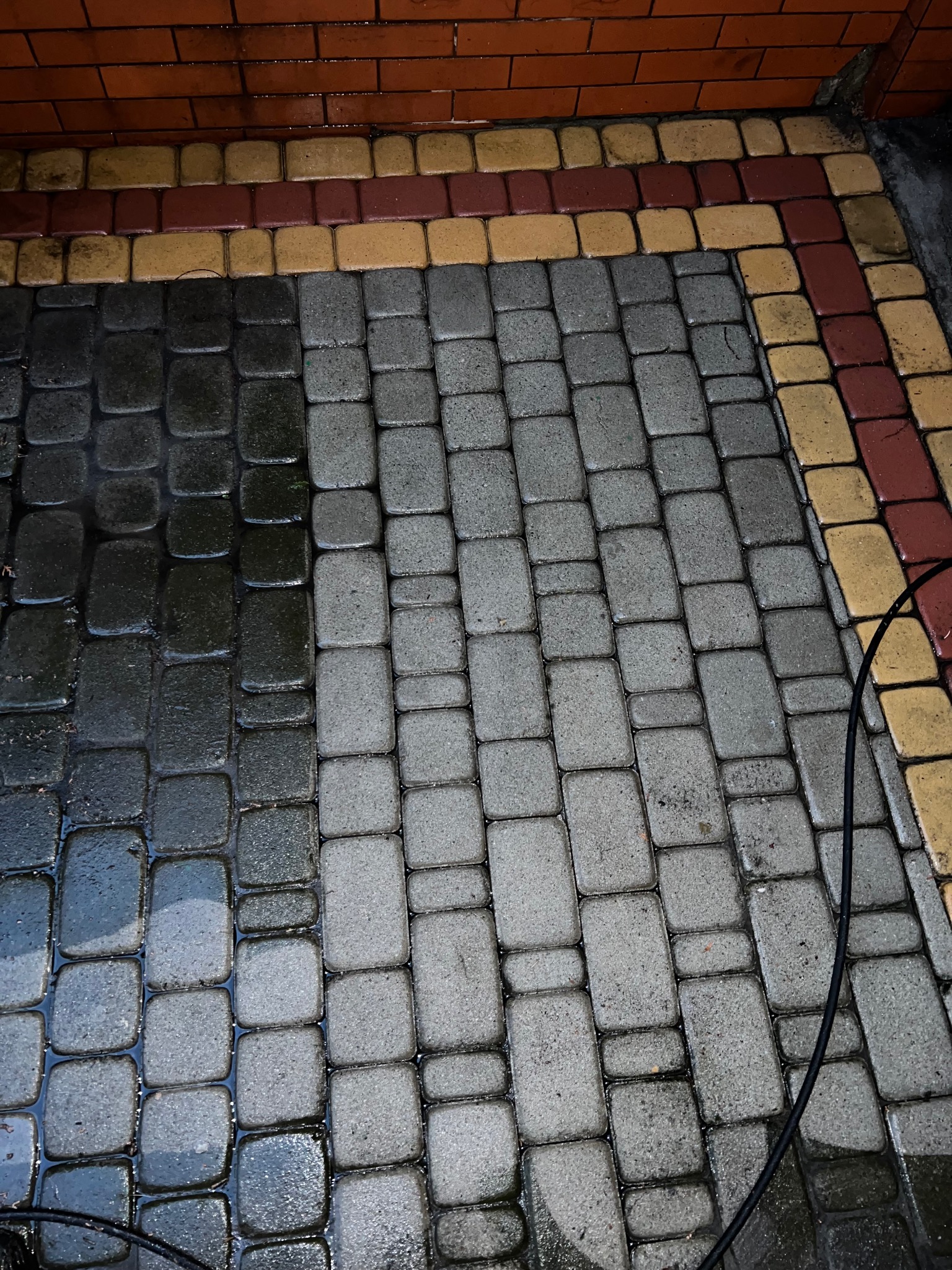 Częściowo wyczyszczona kostka brukowa w Rybniku, widoczna różnica między brudną a umytą powierzchnią, obrzeże z kolorowej kostki.