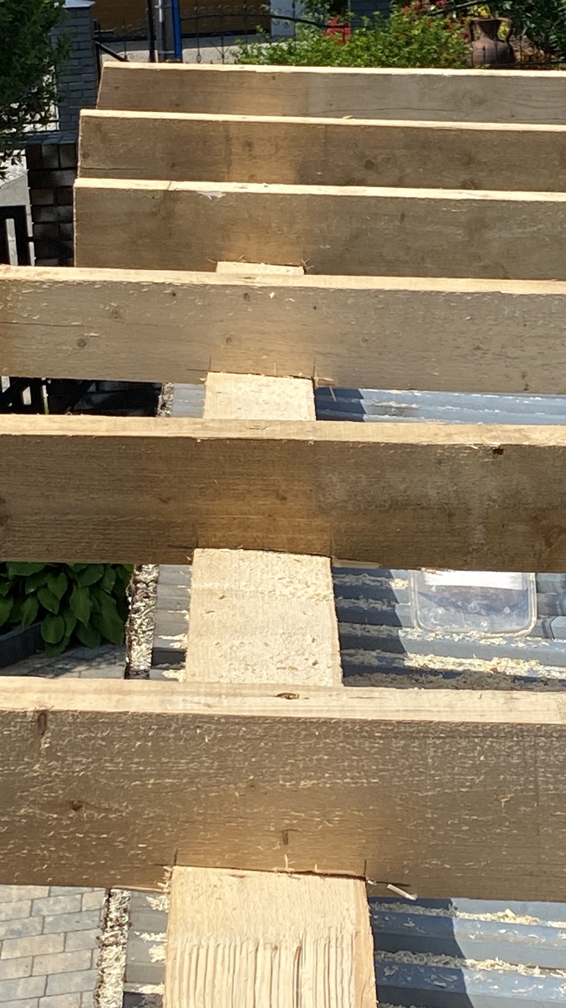 Drewniany szkielet konstrukcji dachu z widocznymi belkami i elementami łączącymi, częściowo pokryty blachą trapezową, z widocznymi śladami obróbki drewna.