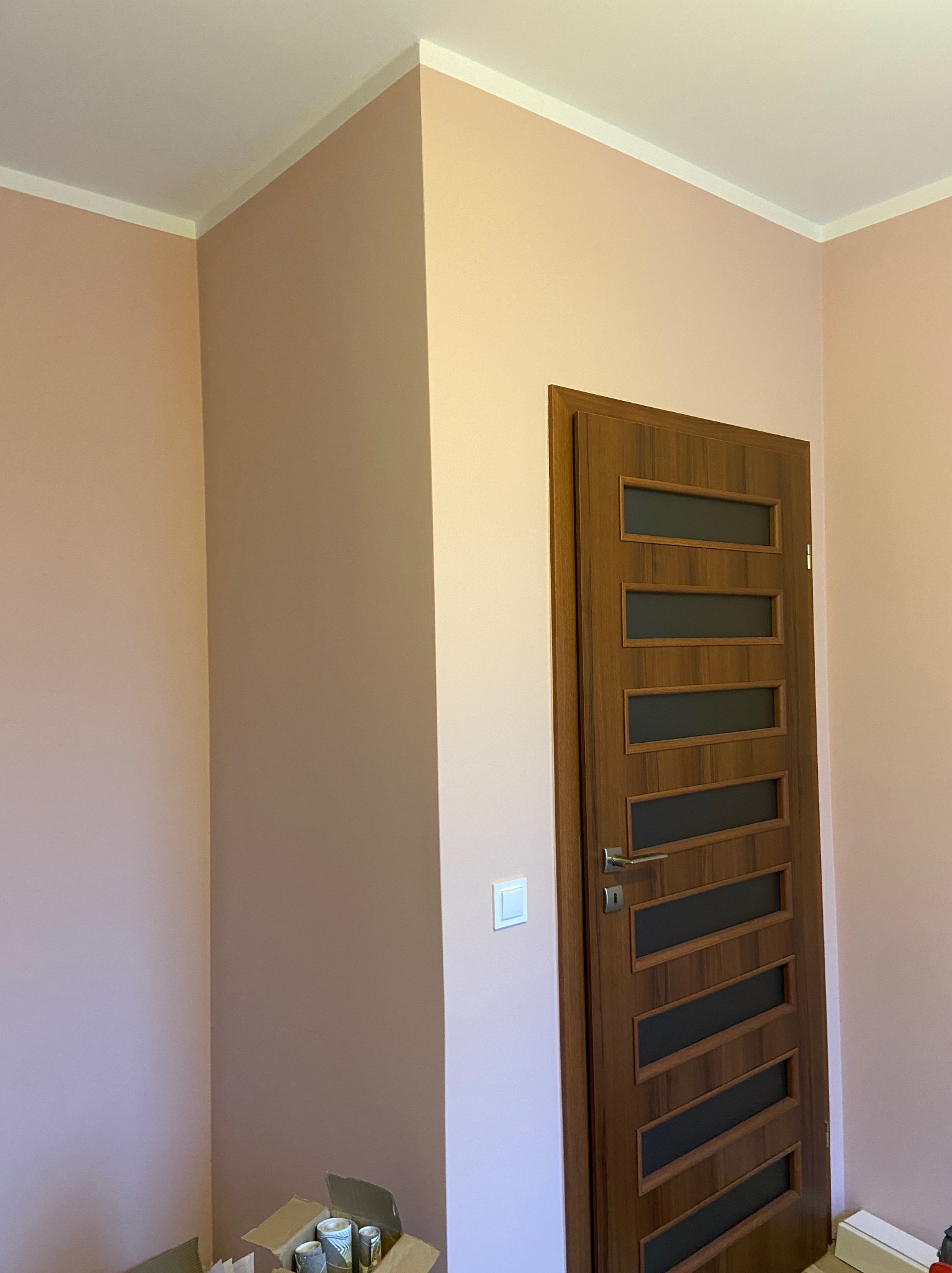 Świeżo pomalowane wnętrze z drzwiami wewnętrznymi z przeszkleniami, widoczna puszka z farbą w rogu pomieszczenia.